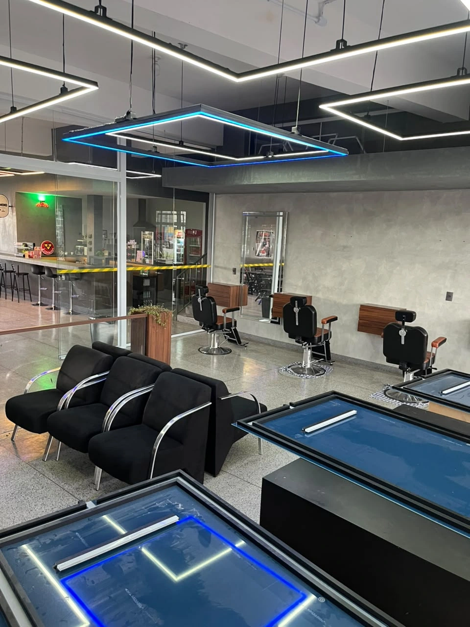 Vista ampla do salão da Sumrak 408 com poltronas de espera e divisória de vidro junto à cafeteria