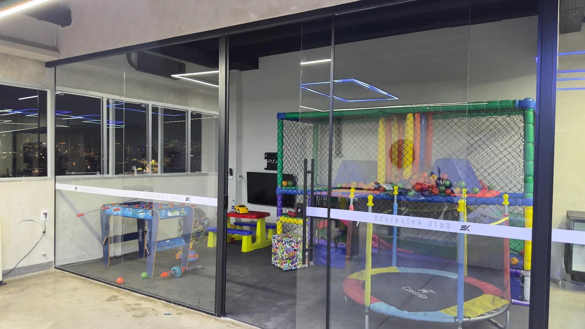 Espaço Kids da Sumrak 408 em sala fechada de vidro com piscina de bolinhas, trampolim, pebolim e mesa infantil