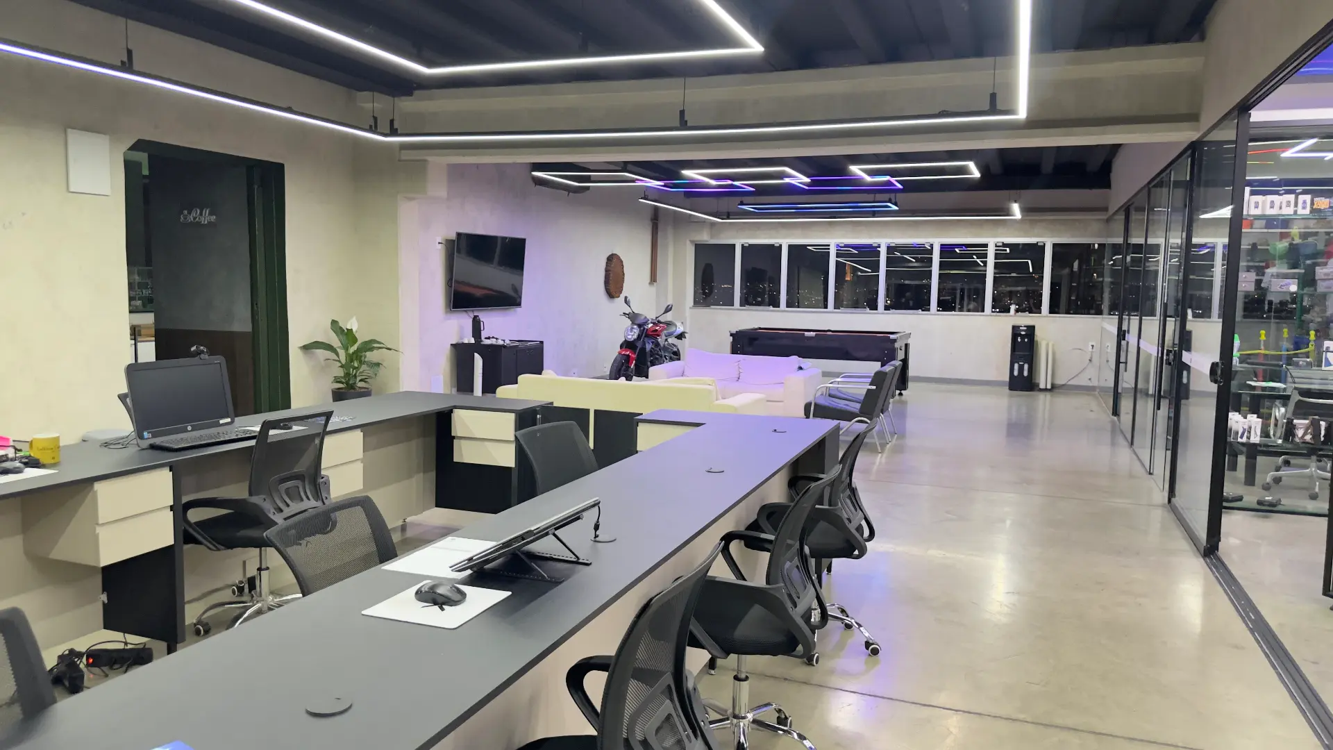 Recepção e área de atendimento da Sumrak 408 com bancadas de trabalho, sofás, mesa de sinuca e acesso à loja